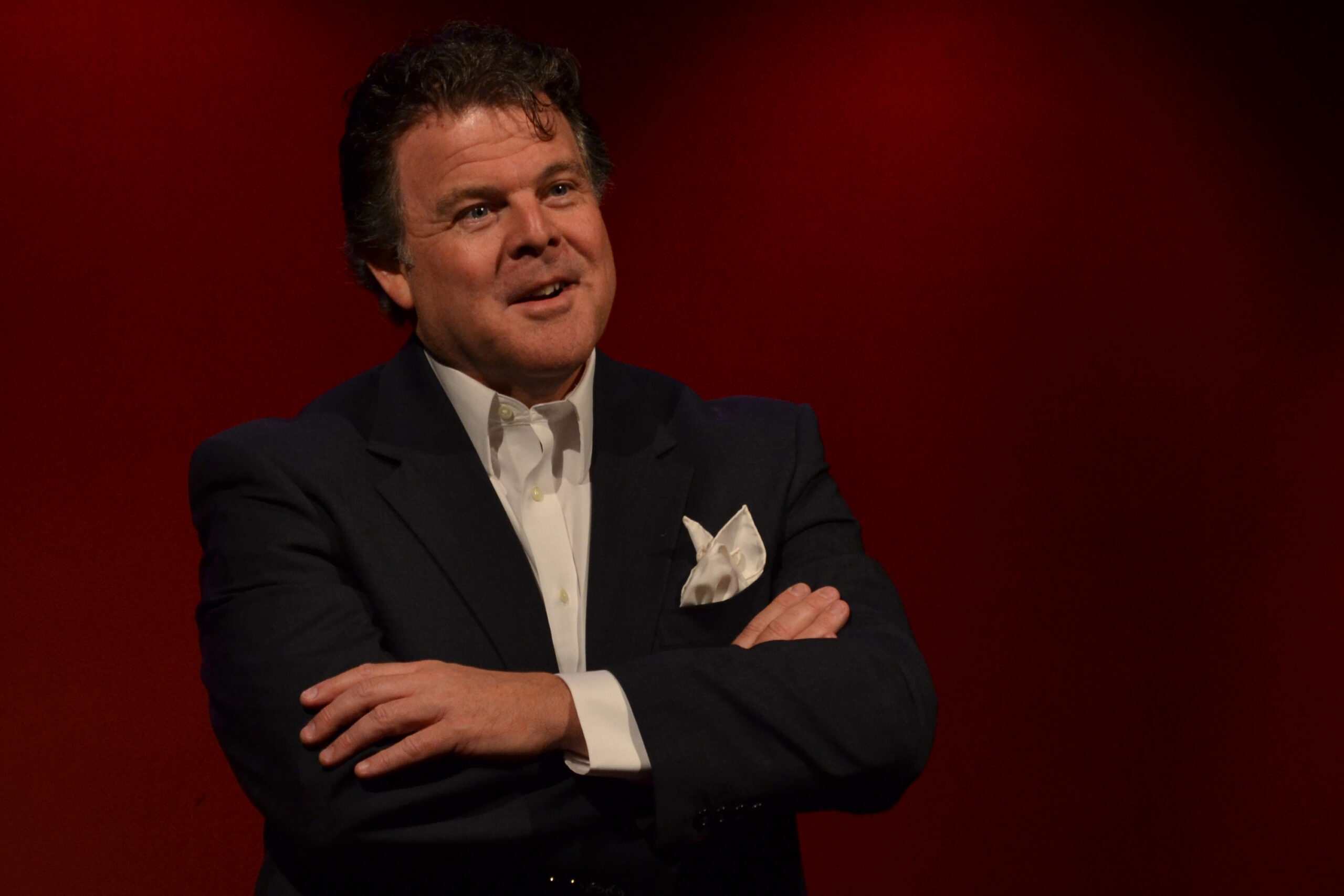 John Carney onstage speaking arms crossed